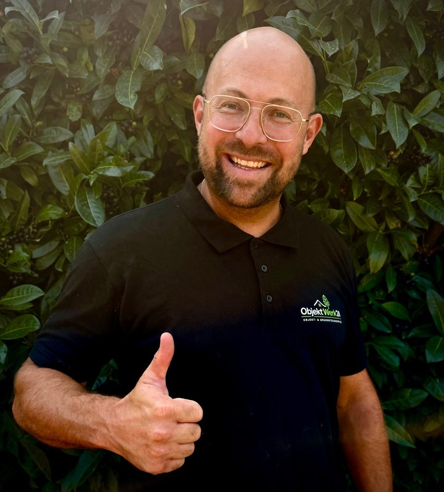 Markus Mroncz, Geschäftsführer von ObjektWerk24, im ObjektWerk24-Polo vor einer Hecke